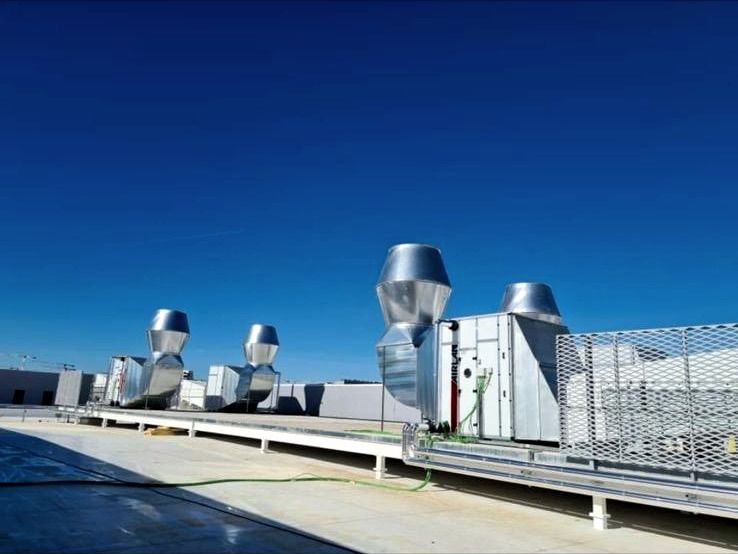Batería de cajas de ventilación con sombreretes de descarga instaladas en la cubierta de una nave industrial