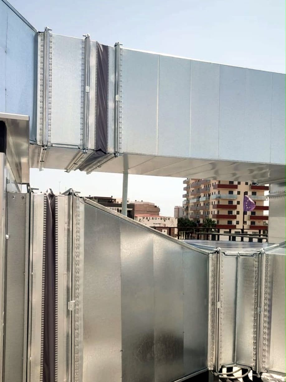 Conductos de ventilación de panel preaislado instalados en la cubierta de un edificio, con juntas flexibles y soportes metálicos
