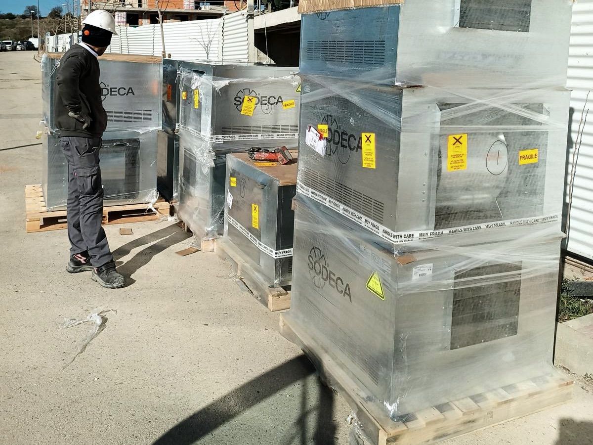 Cajas de ventilación paletizadas recibidas en una obra de nueva construcción, con operario y equipo de protección