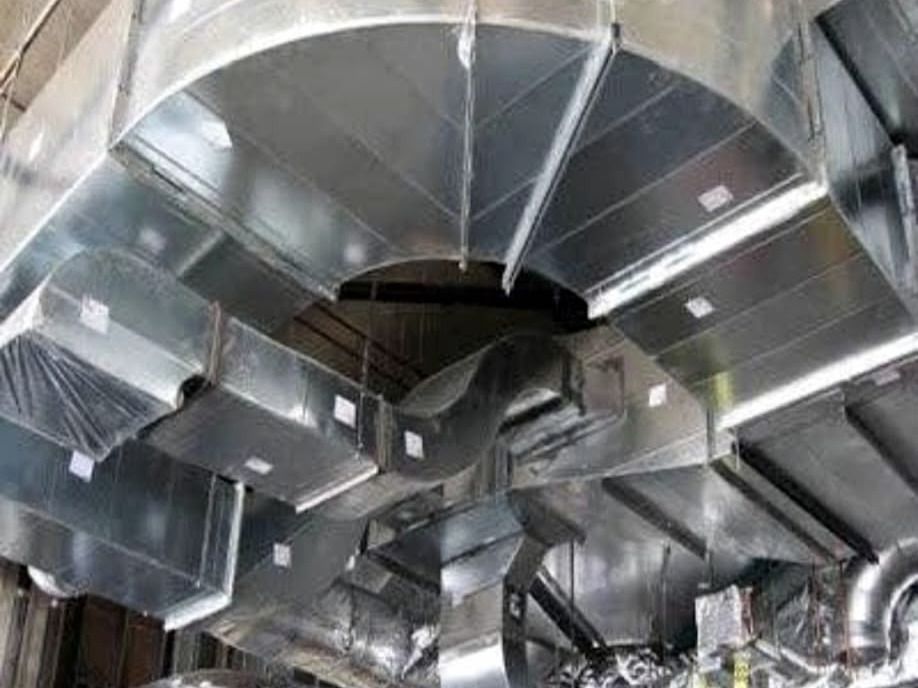 Red densa de conductos metálicos de ventilación con transformaciones y derivaciones bajo el techo de un local