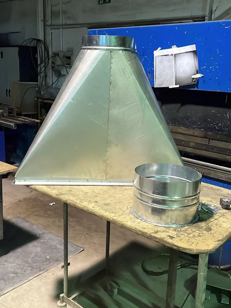Campana de captación piramidal de chapa fabricada a medida en el taller, con la plegadora al fondo