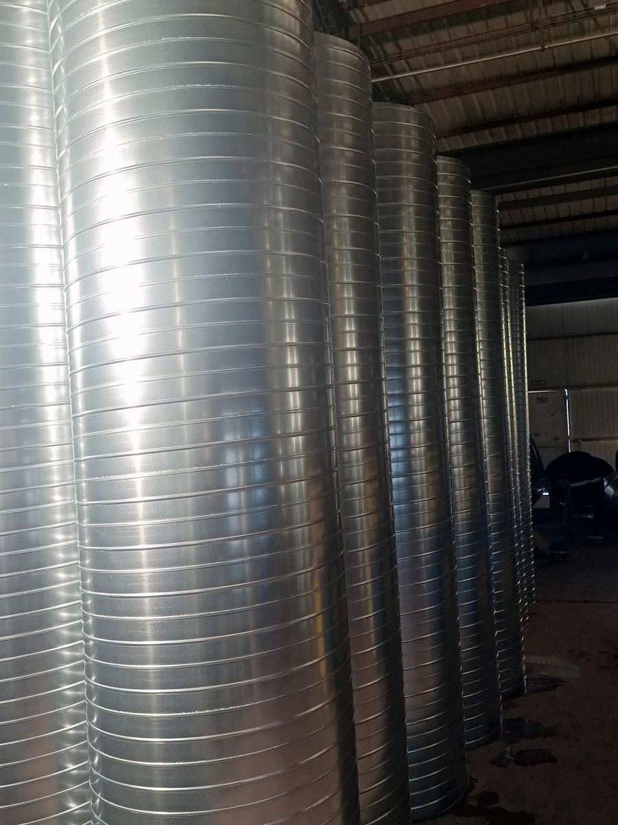 Hilera de conductos helicoidales de chapa galvanizada de gran diámetro en el taller antes del montaje